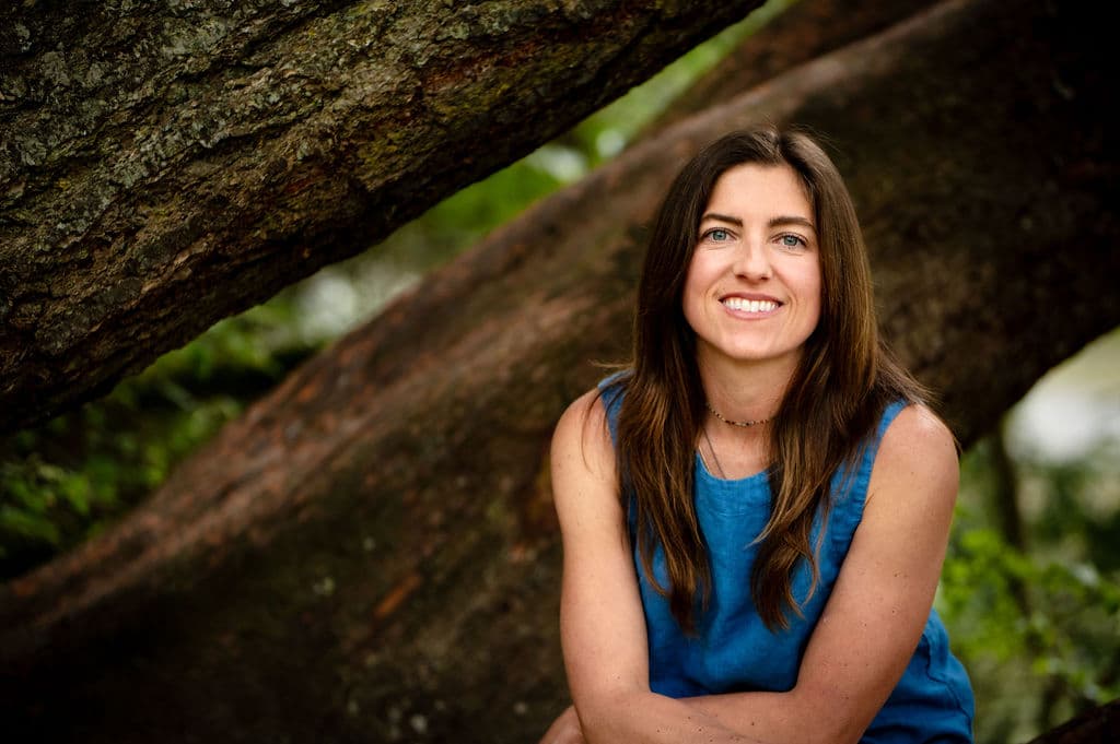 Chrystal smiling beneath the broad branches of a tree.